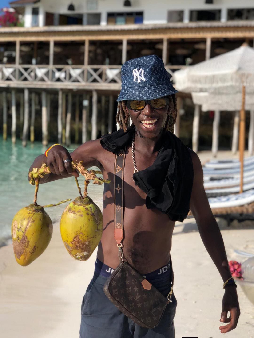 Rama, local Zanzibar guide, smiling on the beach with fresh coconuts
